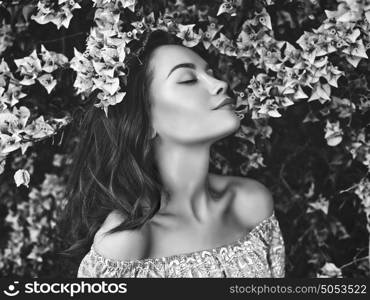 Black and white Outdoor fashion photo of beautiful young woman surrounded by flowers. Spring blossom
