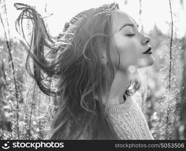 Black and white Outdoor fashion photo of young beautiful lady in autumn landscape with dry flowers. Knitted sweater, wine lipstick. Warm Autumn. Warm Spring