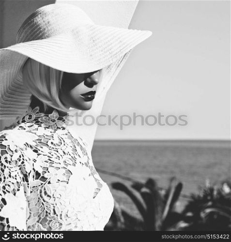 Black and white outdoor fashion photo of young beautiful lady in white hat at the sea. Summer Beach travel. Summer vibes