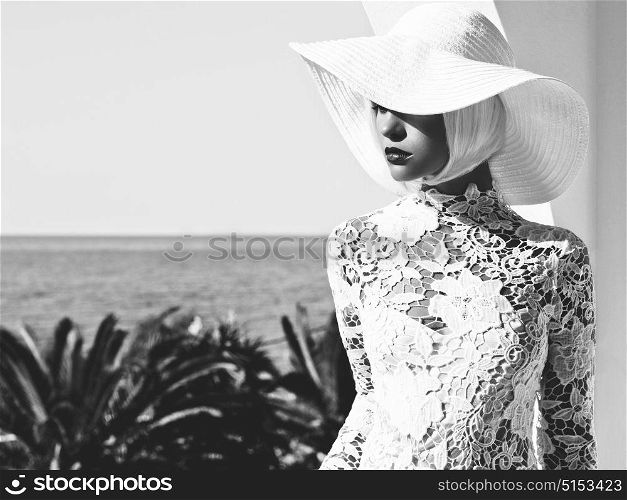 Black and white outdoor fashion photo of young beautiful lady in white hat at sea. Summer Beach travel. Summer vibes