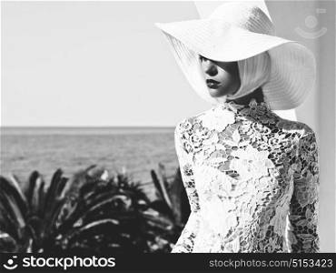 Black and white outdoor fashion photo of young beautiful lady in white hat at sea. Summer Beach travel. Summer vibes