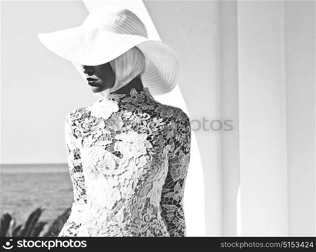Black and white Outdoor fashion photo of young beautiful lady in white hat at sea. Summer Beach travel. Summer vibes