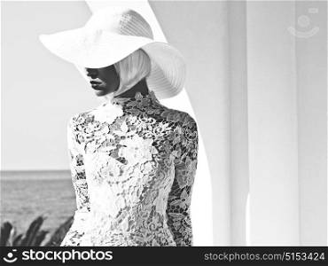 Black and white Outdoor fashion photo of young beautiful lady in white hat at sea. Summer Beach travel. Summer vibes