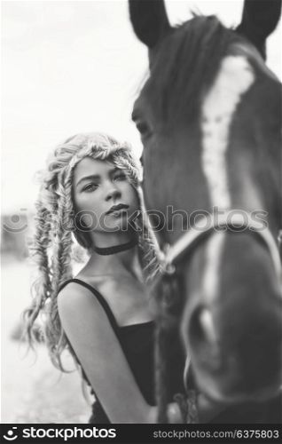 Black and white outdoor fashion portrait of beautiful young girl with horse. Hippie style. Summer vibes. Autumn season