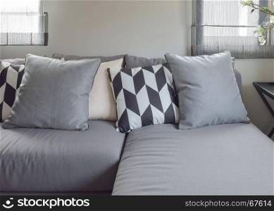 Black and white parallelogram pattern pillows on gray l shape comfy sofa