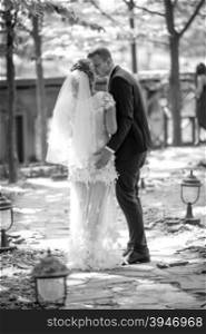 Black and white photo from rear view of bride and groom walking at park