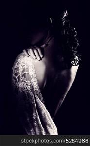 Black and white photo of a gentle woman stands with her back open, wearing tender lace dress gown with open shoulder, sensuality and femininity concept