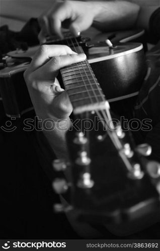 black and white photo of a man&rsquo;s hands playing a guitar