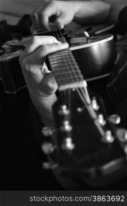 black and white photo of a man&rsquo;s hands playing a guitar