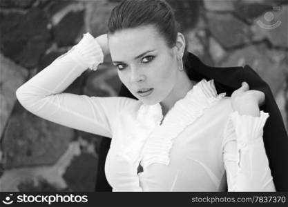 Black and white photo of a young attractive girl with jacket on shoulder. Shallow depth of field.