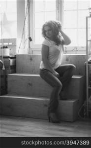 Black and white photo of beautiful curly woman posing on windowsill