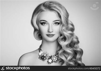 Black and white photo of beautiful woman with elegant hairstyle. Blonde girl with long wavy hair. Jewelry and make-up. Beauty style model