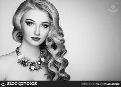 Black and white photo of beautiful woman with elegant hairstyle. Blonde girl with long wavy hair. Jewelry and make-up. Beauty style model