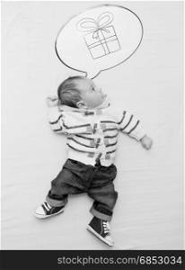Black and white photo of cute little baby boy dreaming of present