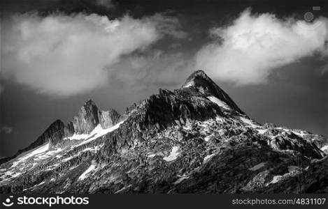 Black and white photo of majestic mountainous landscape, dramatic cloudy sky, beautiful panorama, extreme adventure and travelling concept