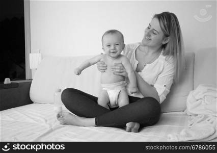 Black and white photo of mother sitting on bed with her baby boy