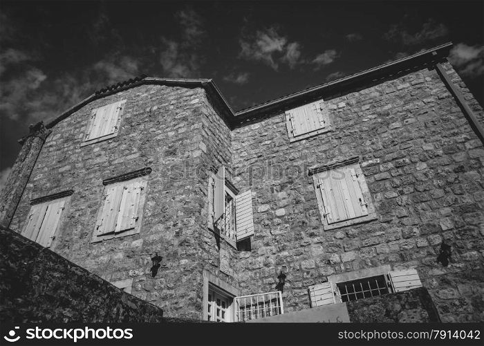 Black and white photo of old stone house at sunny day