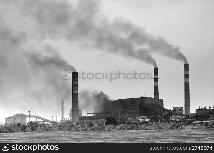 Black and white photo of plant with smoke. Air pollution