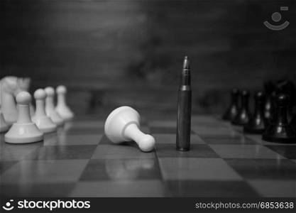 Black and white photo of riffle bullet on chessboard. Concept of power of guns