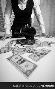 Black and white photo of woman standing behind table with banknotes and piggy bank