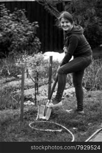 Black and white photo of woman working on garden bed with shovel