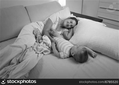 Black and white photo of young mother sleeping with her baby boy in bed