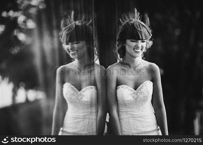 Black and white photo with the noise of a beautiful cheerful young bride in a luxury white dress. displaying the bride in the window outdoors... Black and white photo with the noise of a beautiful cheerful young bride in a luxury white dress. displaying the bride in the window outdoors.