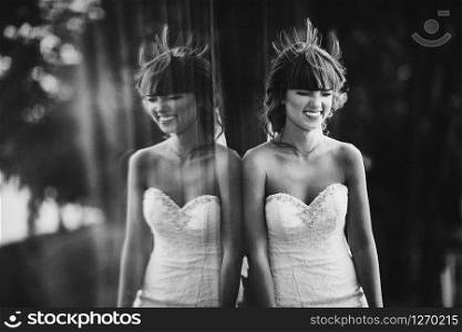 Black and white photo with the noise of a beautiful cheerful young bride in a luxury white dress. displaying the bride in the window outdoors... Black and white photo with the noise of a beautiful cheerful young bride in a luxury white dress. displaying the bride in the window outdoors.