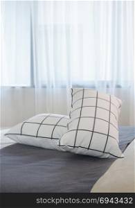 Black and white pillows setting on dark gray bed runner in the bedroom