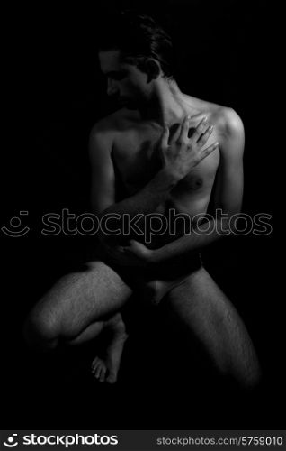 Black and white portrait of a young beautiful naked man on a black background