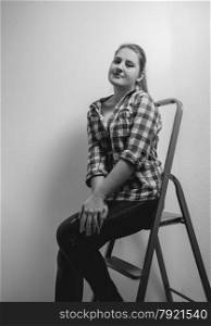 Black and white portrait of beautiful smiling woman in shirt sitting on ladder