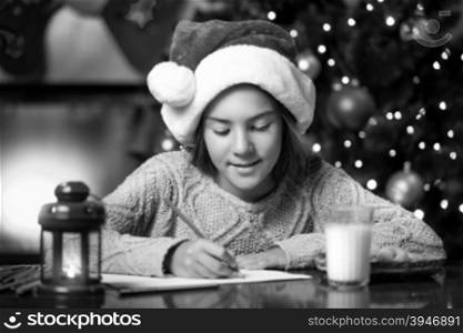Black and white portrait of cute girl writing letter to Santa Claus at living room
