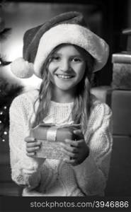 Black and white portrait of cute smiling girl holding Christmas gift box