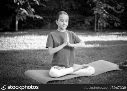 Black and white portrait of cute teen girl meditating at park