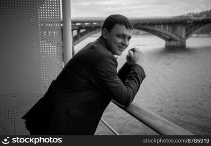 Black and white portrait of handsome businessman posing on balcony