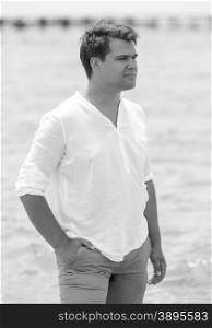 Black and white portrait of handsome young man posing on beach