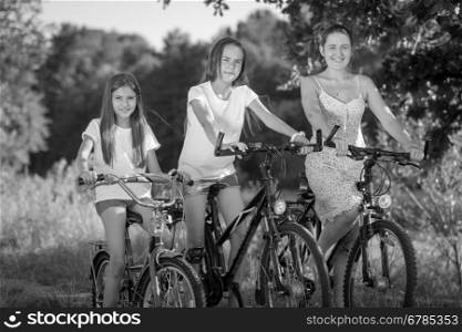 Black and white portrait of happy family cycling at meadow