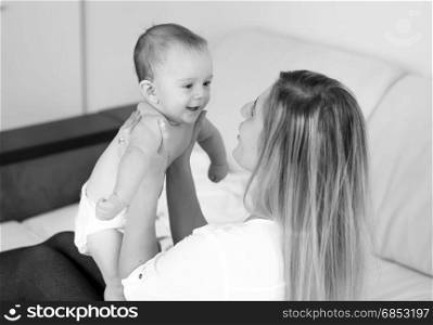 Black and white portrait of happy mother holding baby on hands