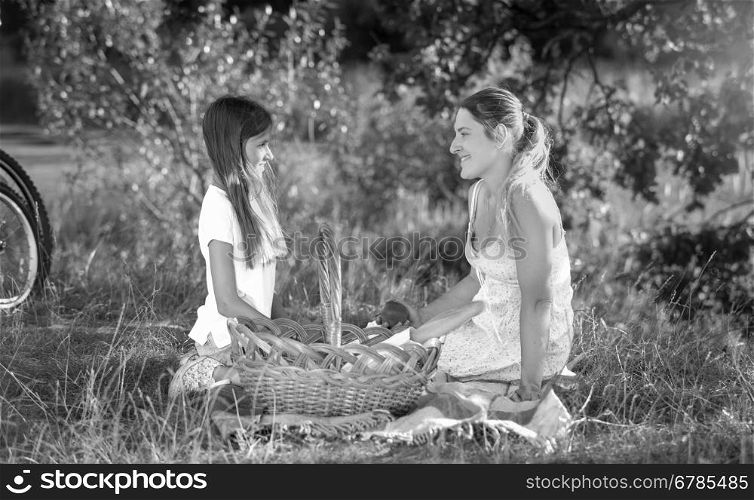 Black and white portrait of happy young woman relaxing with her daughter on picnic