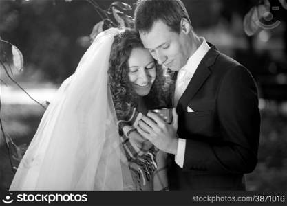 Black and white portrait of just married couple holding cup of tea at park