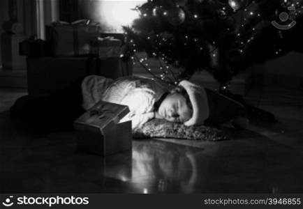 Black and white portrait of little girl lying on floor and looking at present