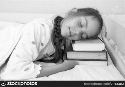 Black and white portrait of little girl sleeping on pile of books at bed