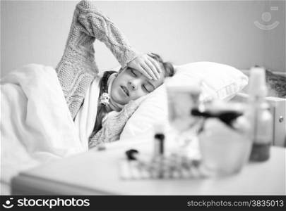 Black and white portrait of little sick girl lying at bed