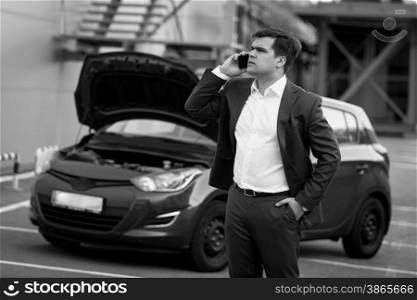 Black and white portrait of man calling in technical service to evacuate broken car