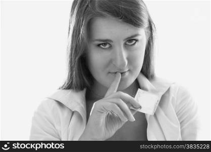 Black and white portrait of sexy slim woman holding condom and looking at camera