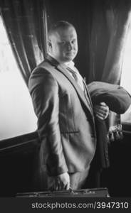 Black and white portrait of smiling man in retro suit posing in train