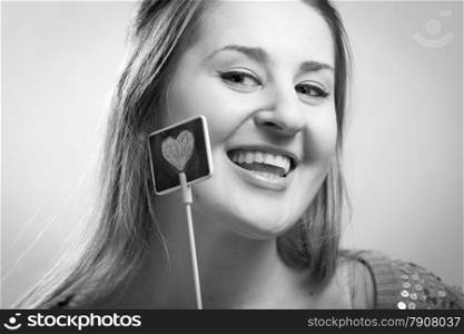 Black and white portrait of smiling woman holding decorative drawn heart