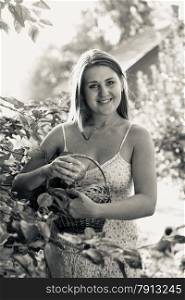 Black and white portrait of smiling woman with basket at garden at sunset