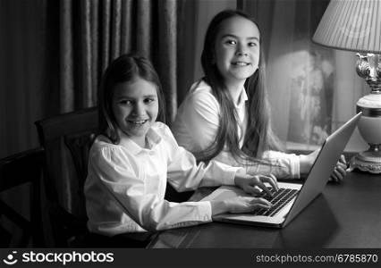 Black and white portrait of two little sisters using laptop