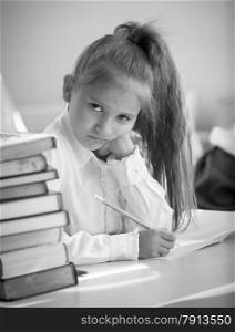 Black and white portrait of upset girl doing homework